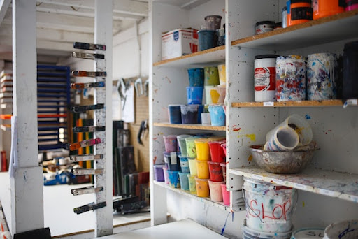 Printing supplies on white shelving inside a studio