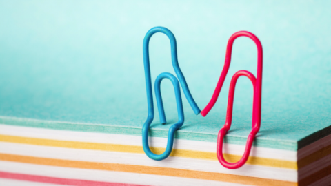 A blue paperclip reaching out for a red paperclip.