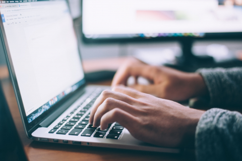 man's hand typing on a laptop keyboard.