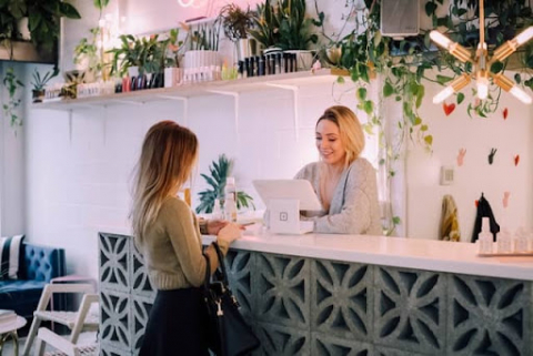 Small business owner chats with a customer at a counter this customer needs a sign.