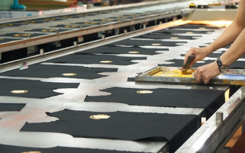 A man screenprinting black tank tops with yellow ink.